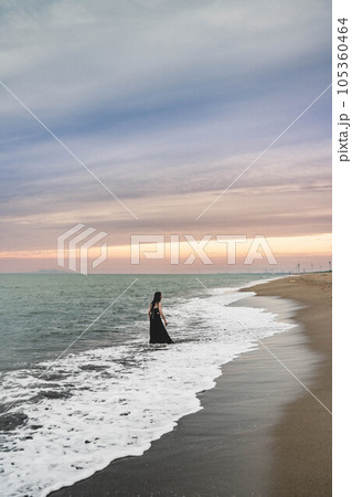 夕暮れの海に入る黒いワンピースの女性 105360464