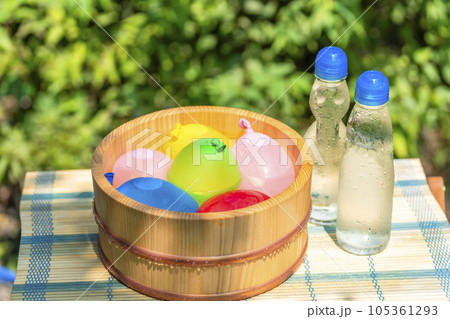 木桶に入れられた水風船と冷えた瓶ラムネ / 夏休み・昭和レトロ・日本の夏の水遊びのイメージ 木桶に入れられた水風船と冷えた瓶ラムネ / 夏休み・昭和レトロ・日本の夏の水遊びのイメージ 105361293