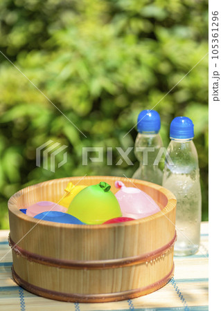 木桶に入れられた水風船と冷えた瓶ラムネ / 夏休み・昭和レトロ・日本の夏の水遊びのイメージ 105361296