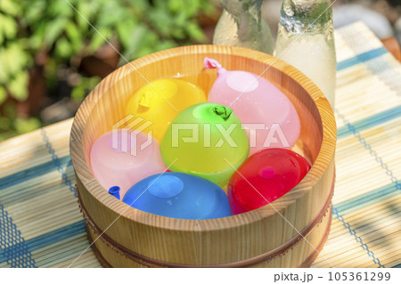 木桶に入れられた水風船と冷えた瓶ラムネ / 夏休み・昭和レトロ・日本の夏の水遊びのイメージ 木桶に入れられた水風船と冷えた瓶ラムネ / 夏休み・昭和レトロ・日本の夏の水遊びのイメージ 105361299