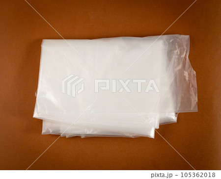 Folded White Plastic Bags on Brown Background, Crumpled Plastic Bag after Shopping, Cellophane Packaging Waste Folded White Plastic Bags on Brown Background, Crumpled Plastic Bag after Shopping, Cellophane Packaging Waste 105362018