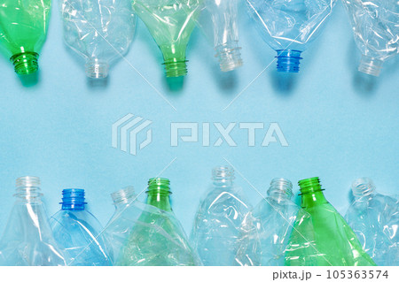 Flat crushed bottle crumpled plastic garbage PET recycling background trash. Flat plastic bottle recycling design blue paper. Row empty bottle PET plastic recycling concept. Reuse. Used. Waste sorting Flat crushed bottle crumpled plastic garbage PET recycling background trash. Flat plastic bottle recycling design blue paper. Row empty bottle PET plastic recycling concept. Reuse. Used. Waste sorting 105363574