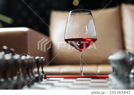 A glass of red wine on a chessboard. A glass of red wine on a chessboard. 105363845