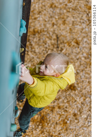 Boy At The Climbing Wall Without A Helmet, Danger At The Climbing Wall. Little Boy Climbing A Rock Wall Indoor 105366114