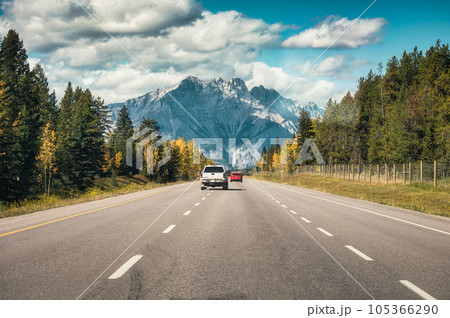 Car driving on highway to rocky mountains in autumn forest at national park 105366290
