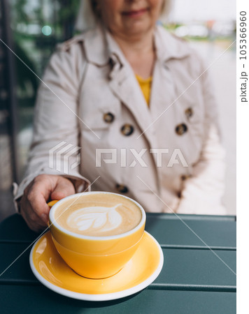 One cup of cappuccino with latte art on table, yellow ceramic cup, place for text. Cafe culture. Concept of easy breakfast. 105366960