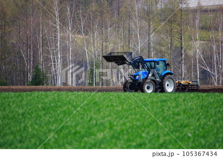 春の畑で畑を耕すトラクター 105367434