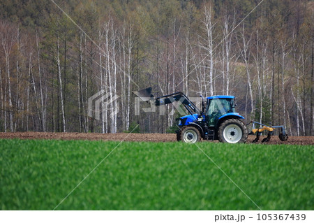 春の畑で畑を耕すトラクター 105367439