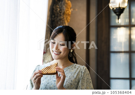 カフェでパンを食べる若い女性 カフェでパンを食べる若い女性 105368404