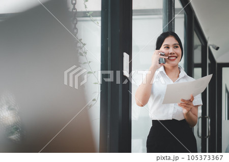 Happy businesswoman talking on mobile phone while analyzing weekly schedule in her paper. 105373367