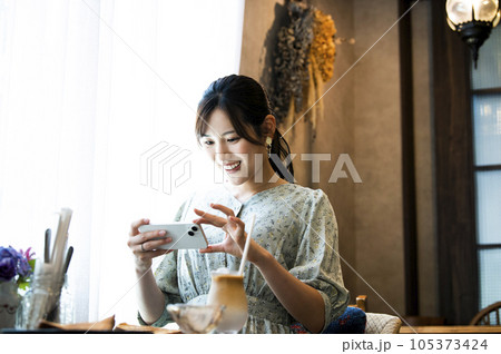 カフェで料理の写真を撮影する若い女性 105373424