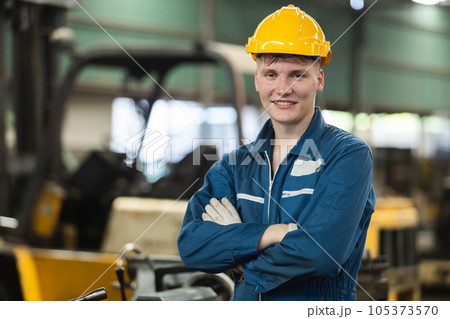 Man engineering wearing uniform safety and yellow hardhat standing at machine in factory industrial Man engineering wearing uniform safety and yellow hardhat standing at machine in factory industrial 105373570
