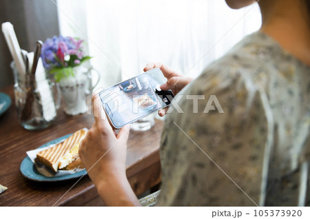 カフェで料理の写真を撮影する若い女性 105373920
