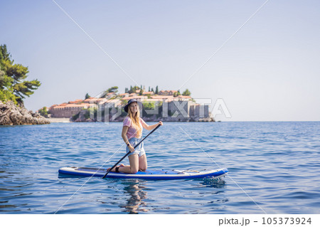 Young women Having Fun Stand Up Paddling in blue water sea near st stefan island in Montenegro. SUP 105373924