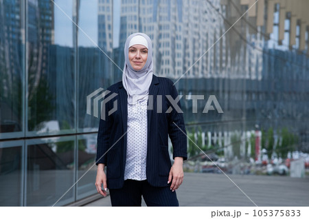 Portrait of smiling pregnant business woman in hijab and suit outdoors. 105375833