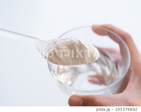 Banan Raw Powder,Banana Flour on Spoon with Water in Glass,Finger Make Flour Banana in Glass on white Background,Traditional Herb in Asian Thailand,Vegetable Food  nature for Diet and Treat Gastritis. 105376692