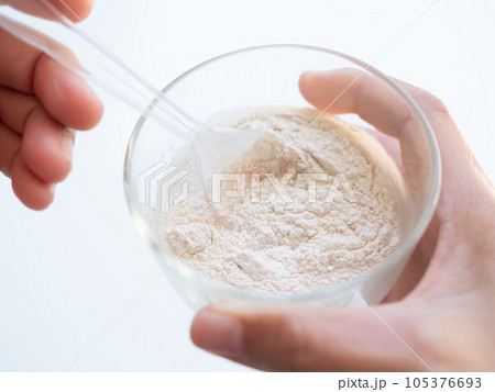 Banan Raw Powder,Banana Flour on Spoon with Water in Glass,Finger Make Flour Banana in Glass on white Background,Traditional Herb in Asian Thailand,Vegetable Food  nature for Diet and Treat Gastritis. 105376693