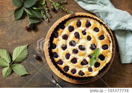 Sweet pie with blackberry and custard on wooden table. Homemade blackberry pie. Vegan gluten-free pastry, vegan desserts. View from above. Sweet pie with blackberry and custard on wooden table. Homemade blackberry pie. Vegan gluten-free pastry, vegan desserts. View from above. 105377738
