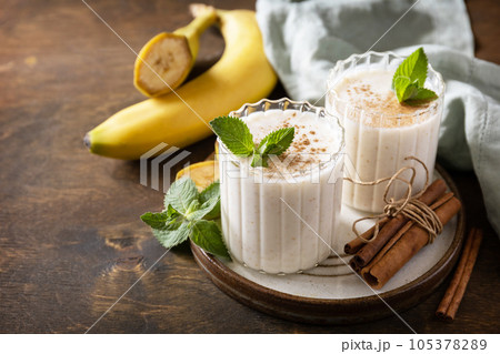 Detox menu. Banana smoothie with cinnamon in drinking glass on a wooden background. Copy space. Detox menu. Banana smoothie with cinnamon in drinking glass on a wooden background. Copy space. 105378289