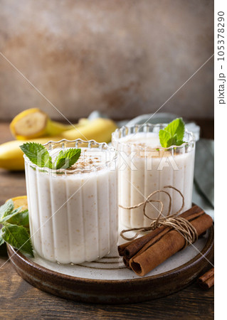 Banana smoothie with cinnamon in drinking glass on a wooden background. Detox menu. Copy space. Banana smoothie with cinnamon in drinking glass on a wooden background. Detox menu. Copy space. 105378290