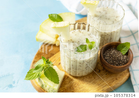 Cold fresh melon smoothies with chia seeds on wooden board on a stone background. Summer drink beverage, healthy food concept. Fresh seasonal smoothies. Copy space. 105378314