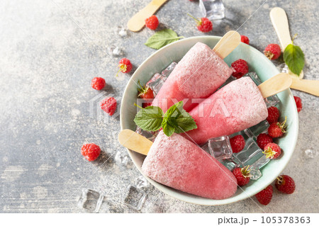 Ice cream. Summer dessert. Homemade raspberry popsicles with yogurt and raspberries on a gray stone background. Copy space. Ice cream. Summer dessert. Homemade raspberry popsicles with yogurt and raspberries on a gray stone background. Copy space. 105378363