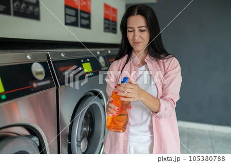 Woman in laundromat showing bad cleaning detergent. 105380788