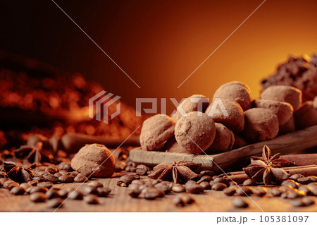 Chocolate truffles with cinnamon, anise, and coffee beans on a wooden table. 105381097