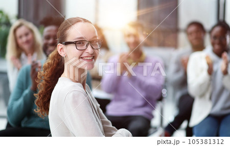 Smiling businesswoman in glasses looking at camera at a seminar Smiling businesswoman in glasses looking at camera at a seminar 105381312