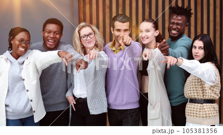 Group of cheerful young people standing close to each other and pointing you Group of cheerful young people standing close to each other and pointing you 105381356