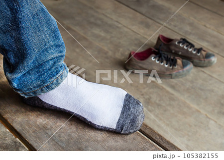 Men wearing socks put a foot on a wooden foor Men wearing socks put a foot on a wooden foor 105382155