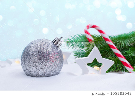 Silver ball, stars lanterns, fir branches and candy cane on snow. Soft focus. Concept of Christmas, New Year. Copy space Silver ball, stars lanterns, fir branches and candy cane on snow. Soft focus. Concept of Christmas, New Year. Copy space 105383045