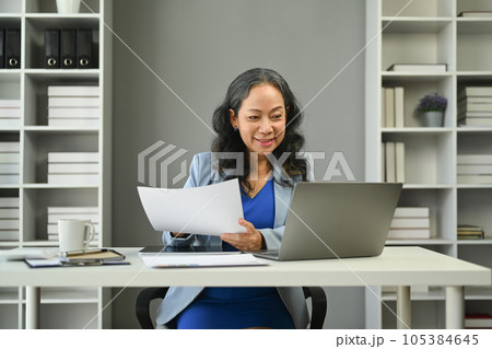 Middle age businesswoman looking at laptop screen, analyzing financial data, stock market information at workstation 105384645