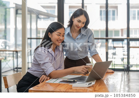 Two young Asian businesswoman discuss investment project working and planning strategy. Business people talking together with laptop computer at office Two young Asian businesswoman discuss investment project working and planning strategy. Business people talking together with laptop computer at office 105384850