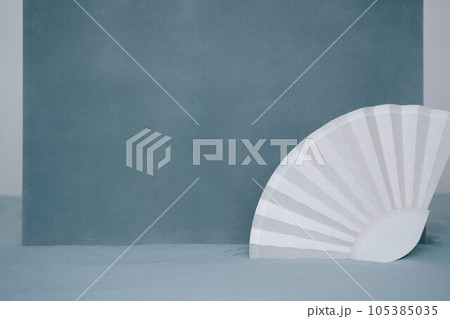 White paper fan joebon on blue textured background. Soft monochrome image summer house party accessoires 105385035