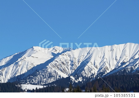 Mountain with snow. Alps. Switzerland. Panoramic view of the Snowy Alps and blue sky around the Titlis mountain. French Alps. Alpine mountains. Descent peaks on the Austrian snow slopes. ski slopes. Mountain with snow. Alps. Switzerland. Panoramic view of the Snowy Alps and blue sky around the Titlis mountain. French Alps. Alpine mountains. Descent peaks on the Austrian snow slopes. ski slopes. 105385531