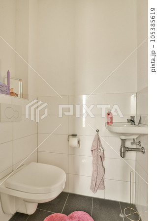 a white bathroom with pink towels on the floor and a toilet in the corner next to the sink is visible a white bathroom with pink towels on the floor and a toilet in the corner next to the sink is visible 105385619