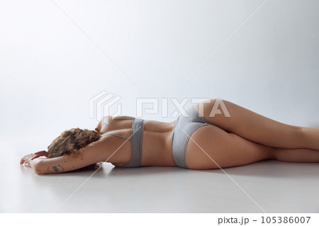 Back view image of slim female body, back and buttocks. Model posing in underwear over white studio background 105386007