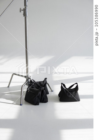Three sand bags on a studio cyclorama with a stand, c-stand. Photography studio sandbags for photographic equipment. Ballast for lighting stands. 105386990