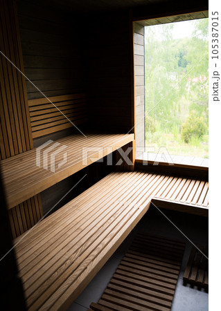 Interior of Finnish sauna, classic wooden sauna with hot steam. Relax in hot sauna with steam. Wooden interior baths, wooden benches and loungers accessories for sauna, spa complex. 105387015
