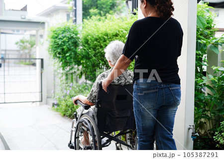 Caregiver help Asian elderly woman disability patient sitting on wheelchair in hospital, medical concept. 105387291