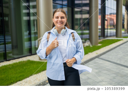 Beautiful caucasian student woman with backpack smiling happy using headphones at the college. Beautiful caucasian student woman with backpack smiling happy using headphones at the college. 105389399