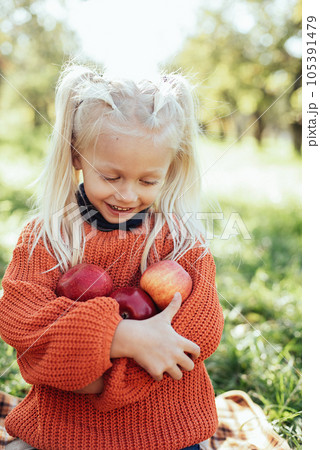 Child picking apples on farm in autumn. Little girl playing in tree orchard. Healthy nutrition. Cute little girl eating red delicious fruit. Harvest Concept. Apple picking. Child picking apples on farm in autumn. Little girl playing in tree orchard. Healthy nutrition. Cute little girl eating red delicious fruit. Harvest Concept. Apple picking. 105391479