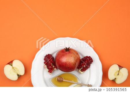 Honey, apples and pomegranate on orange background, flat lay. Rosh Hashanah holiday 105391565