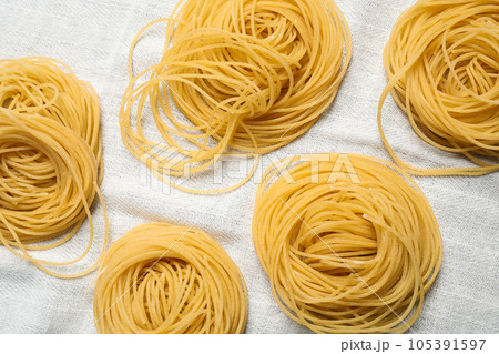 Capellini pasta on white tablecloth, flat lay 105391597
