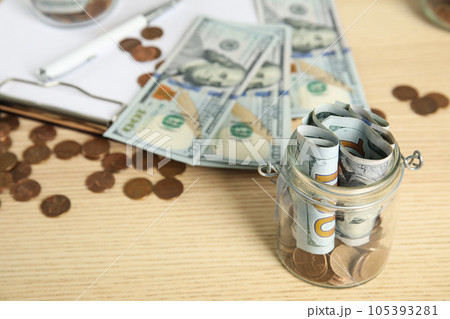 Glass jar with money on wooden table. Space for text 105393281