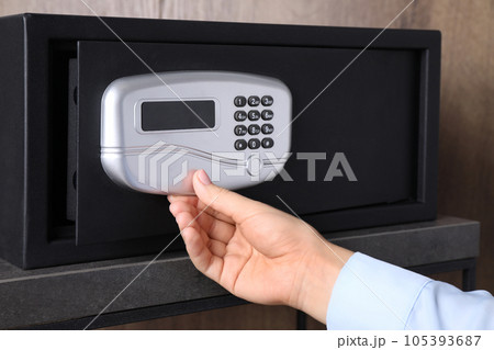 Woman opening black steel safe with electronic lock, closeup Woman opening black steel safe with electronic lock, closeup 105393687