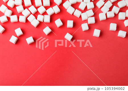 Refined sugar cubes on red background, top view. Space for text 105394002
