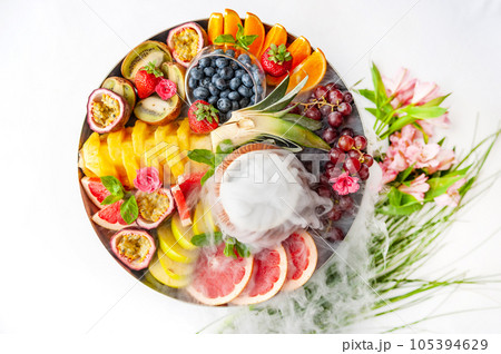 Raw fruits berries assortment platter on the plate, on the white table Raw fruits berries assortment platter on the plate, on the white table 105394629