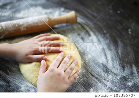 Hands, rolling-pin and dough for bread, pasta or pizza on wooden table 105395707